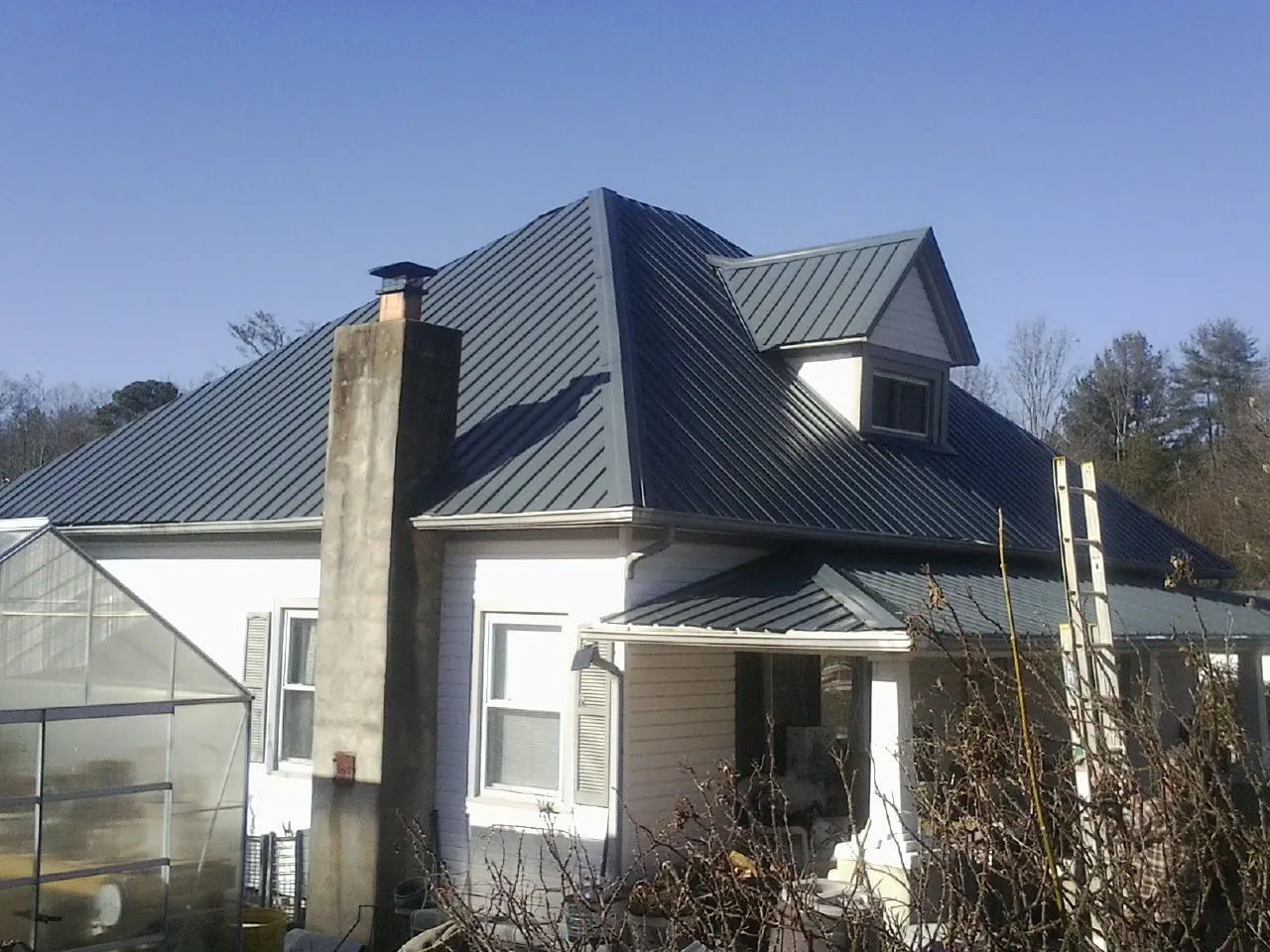 Dark blue standing seam metal roof on a white farmhouse with dormer — Slate & Tile Roof Repair by Roofing Brothers in Diagonal
