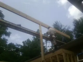 Carpenter setting a ridge beam over a new addition frame — Ice Dam Removal by Roofing Brothers in Diagonal