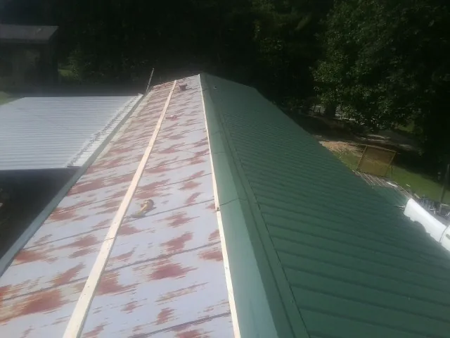 Old rusted panels beside newly installed green metal roofing — Wind Damage Roof Repair by Roofing Brothers in Diagonal