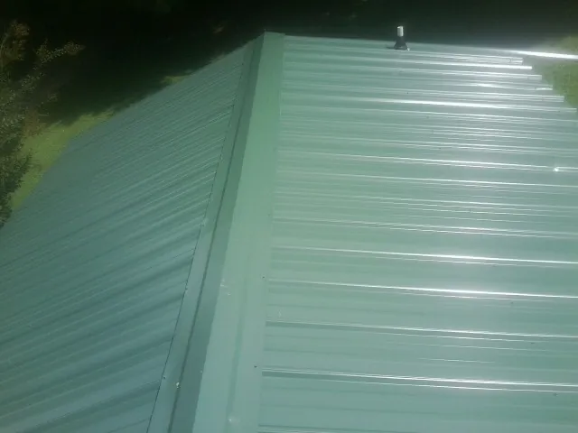 New green metal panels meeting at the ridge of a roof — Flat Roof Repair work by our crew in Diagonal