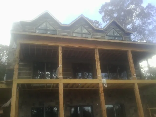 Dormers and porch framing on a large log home under construction — Roof Coating work by our crew in Diagonal