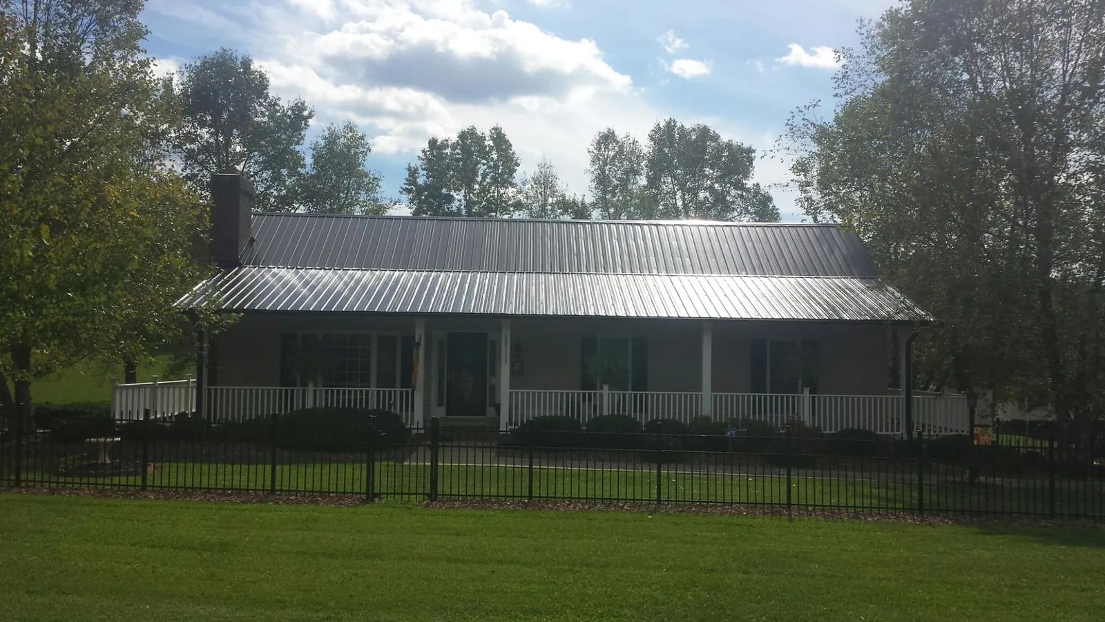 Gray metal roof on a brick ranch with a full width front porch — Gutter Guard Installation work by our crew in Diagonal