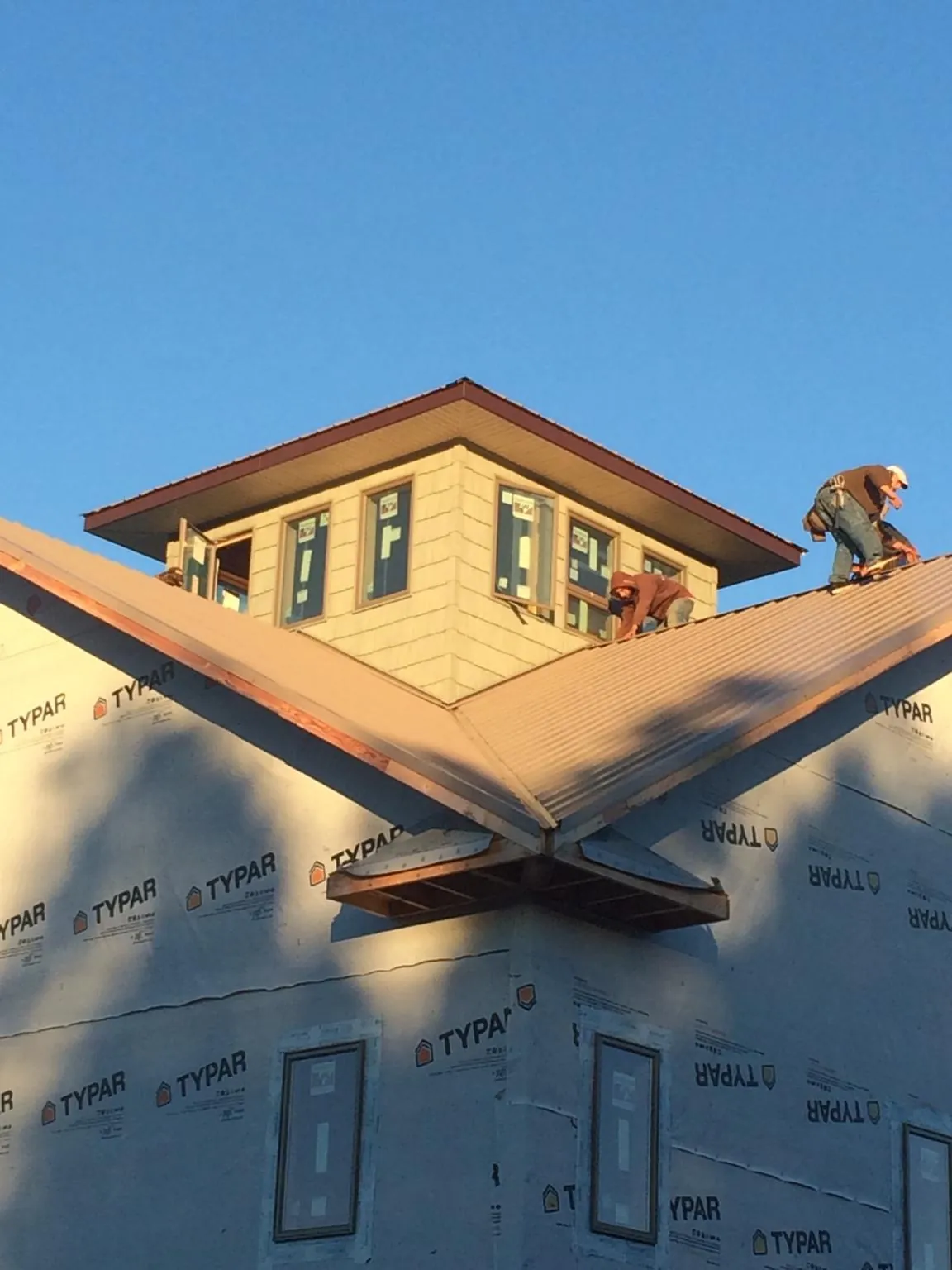 Roofers working around a rooftop cupola on a new metal roof at sunset — Roof Waterproofing in Diagonal by Roofing Brothers
